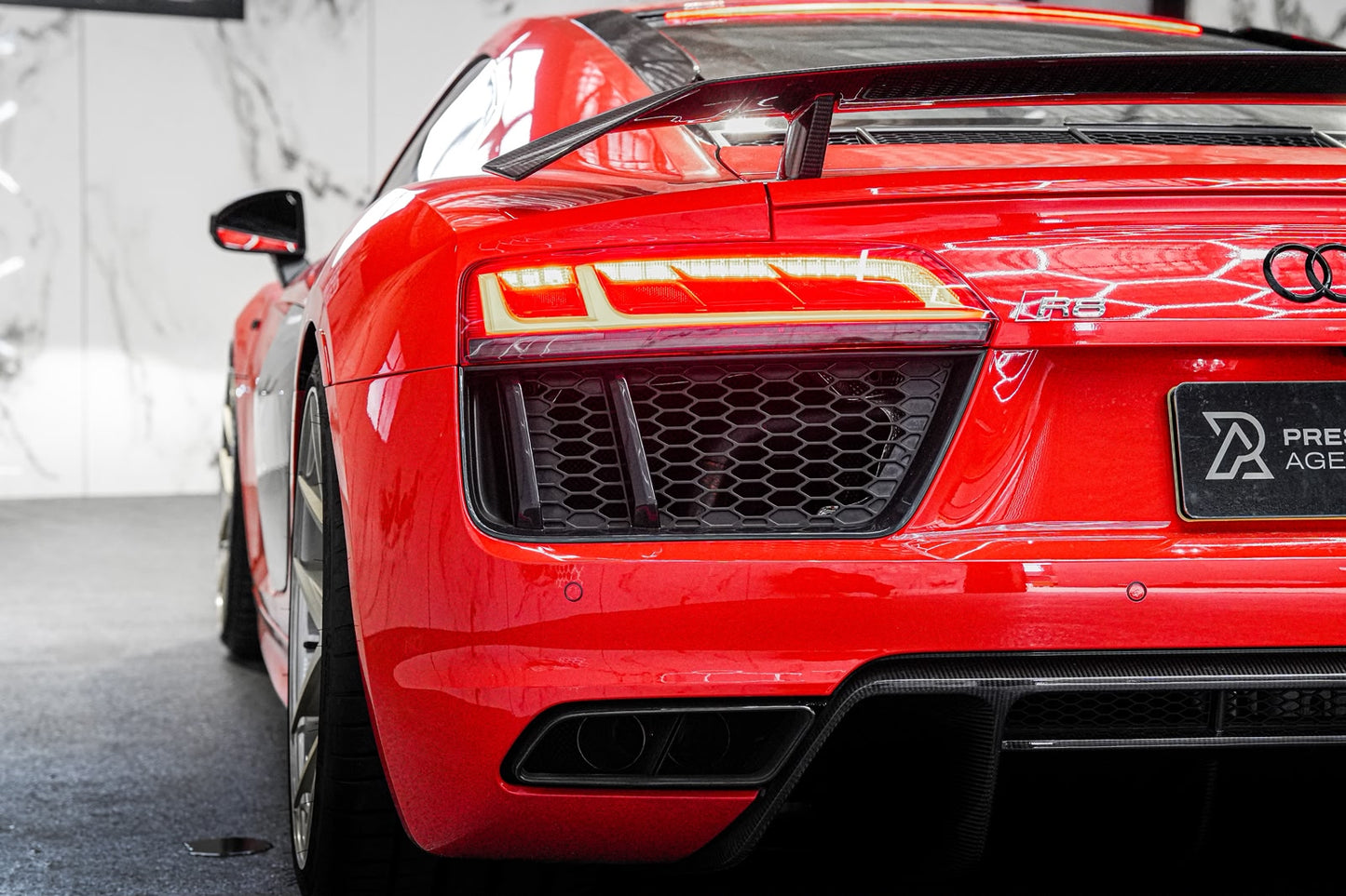 Red Audi R8 sports car with a visible badge in a showroom setting
