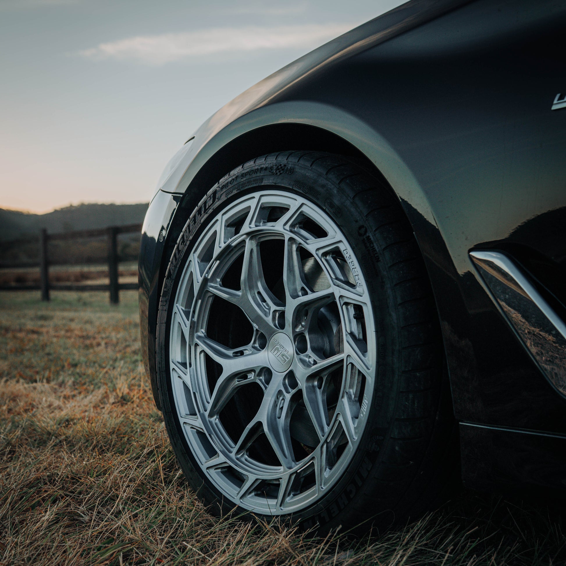 Close-up of a car wheel with a detailed rim in an outdoor setting