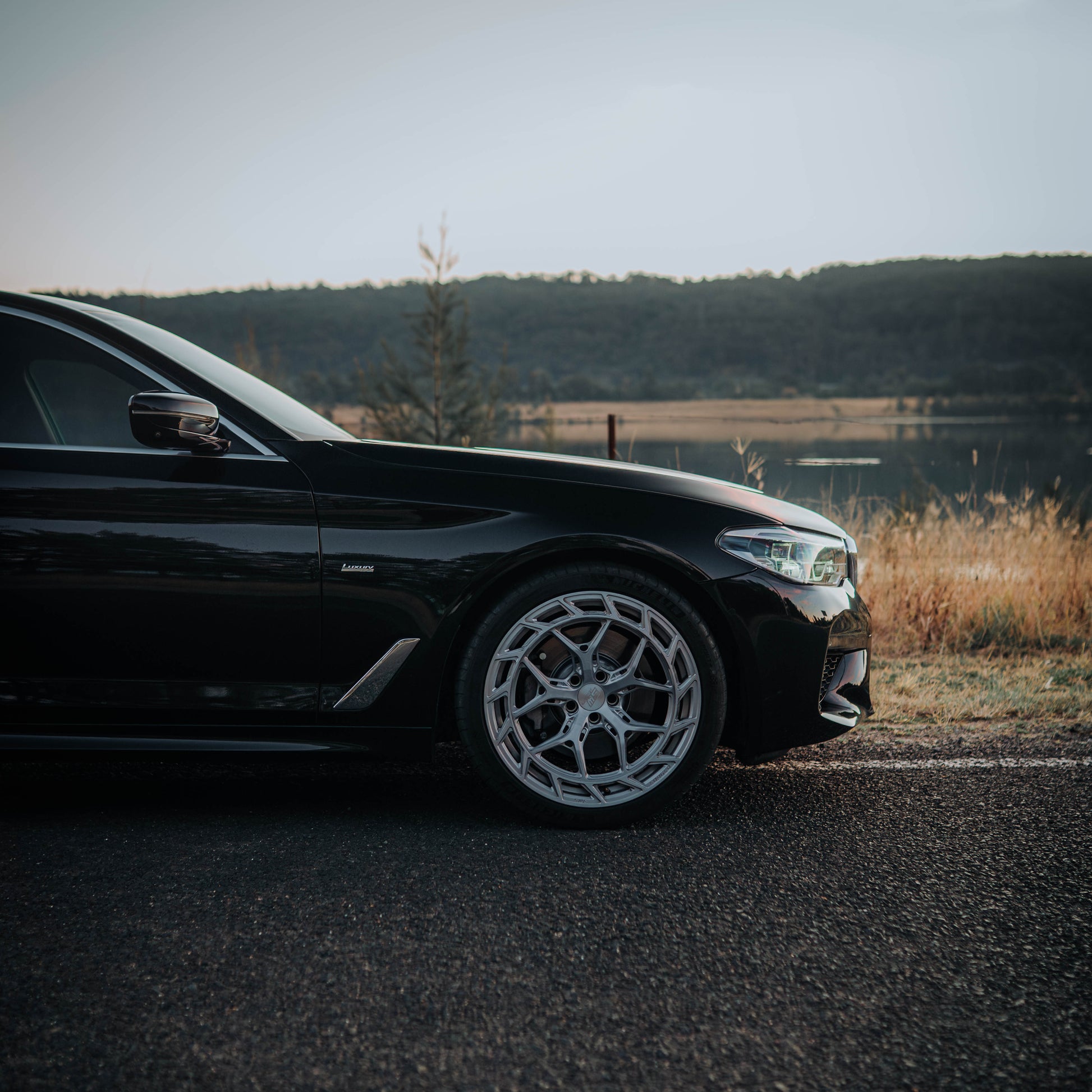 Black car parked on a road with a scenic background