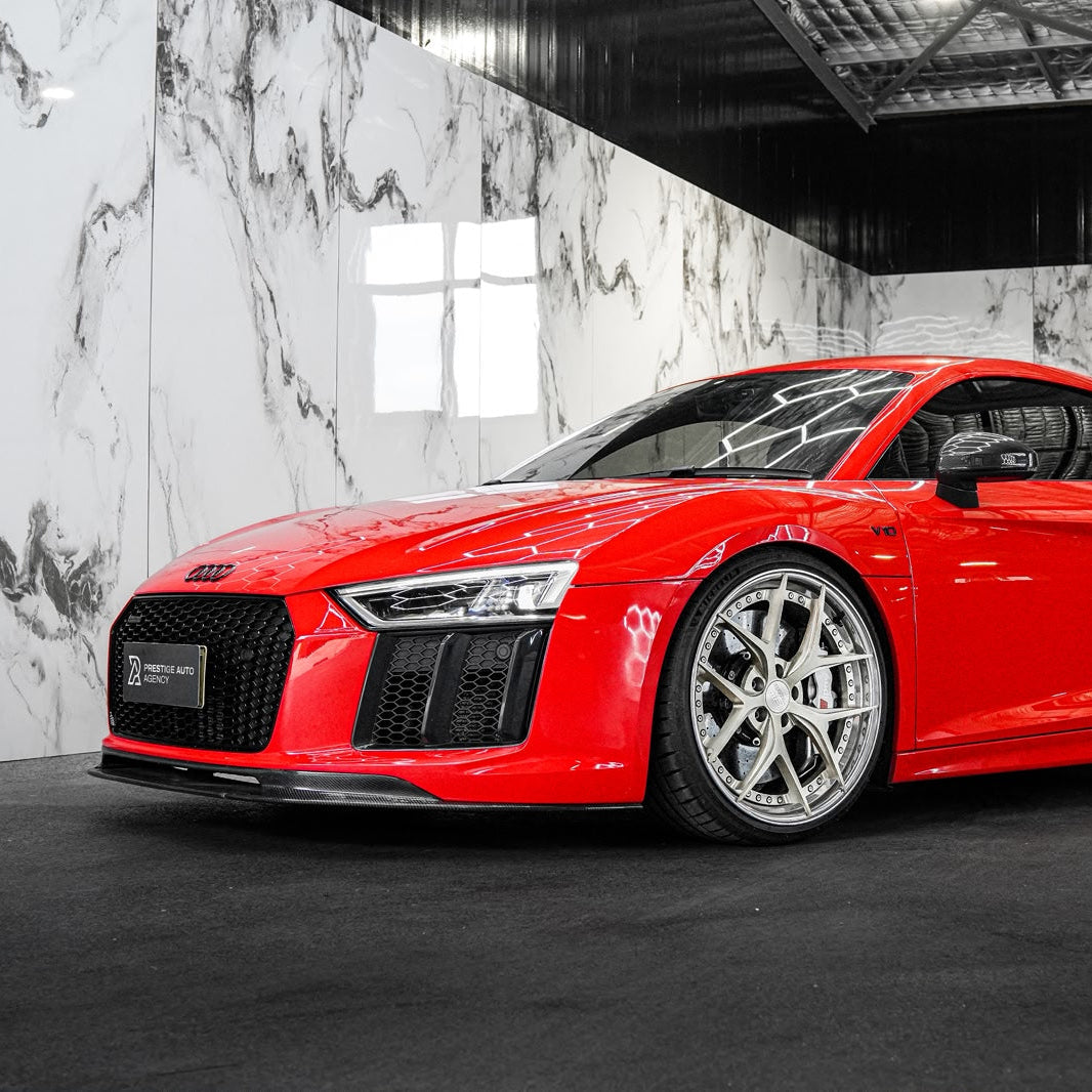 Red Audi car in a showroom with marble walls and large windows.