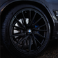Close-up of a black car wheel with BMW logo on a dark background