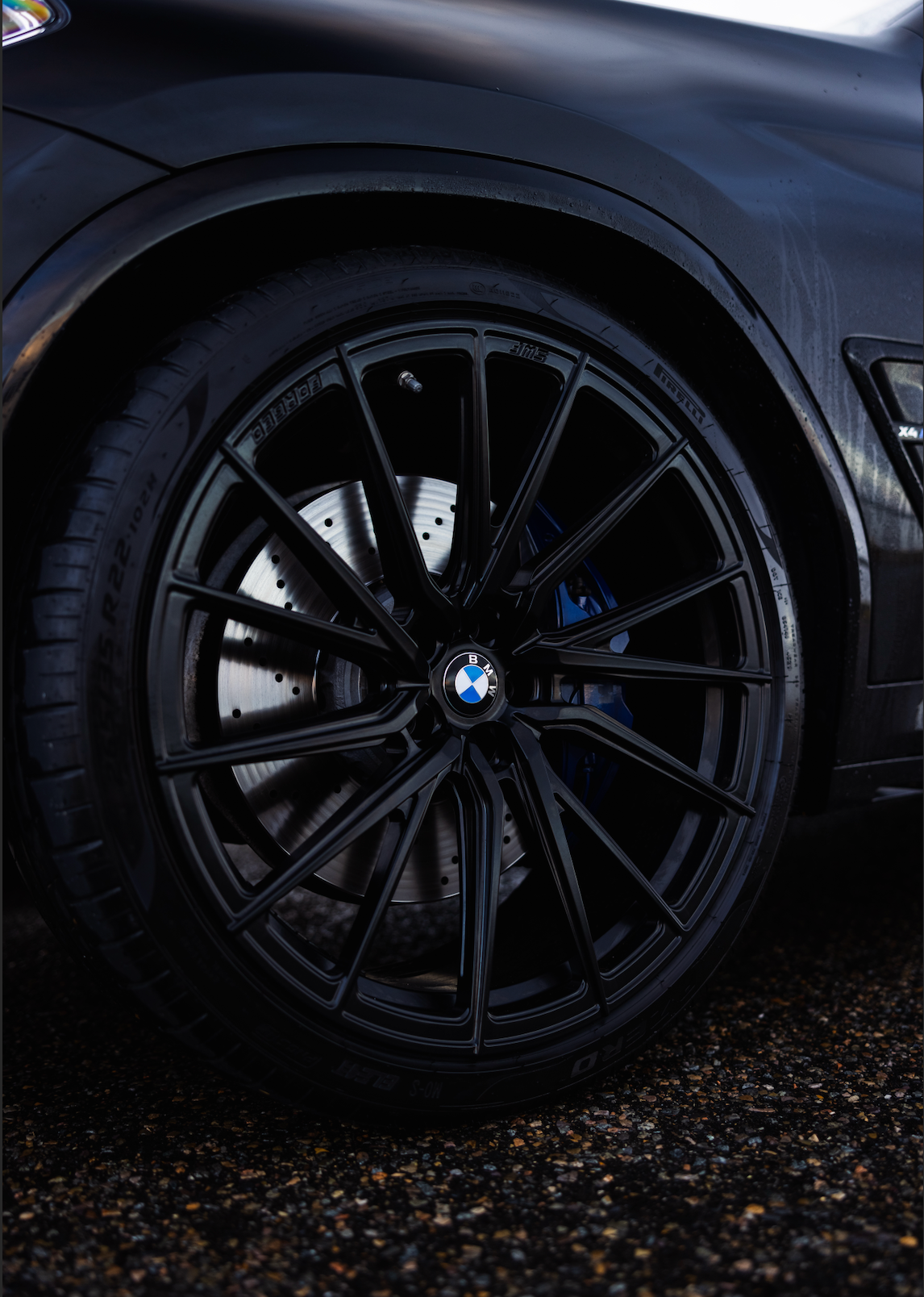Close-up of a black car wheel with BMW logo on a dark background