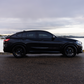Black SUV parked by a waterfront on a cloudy day