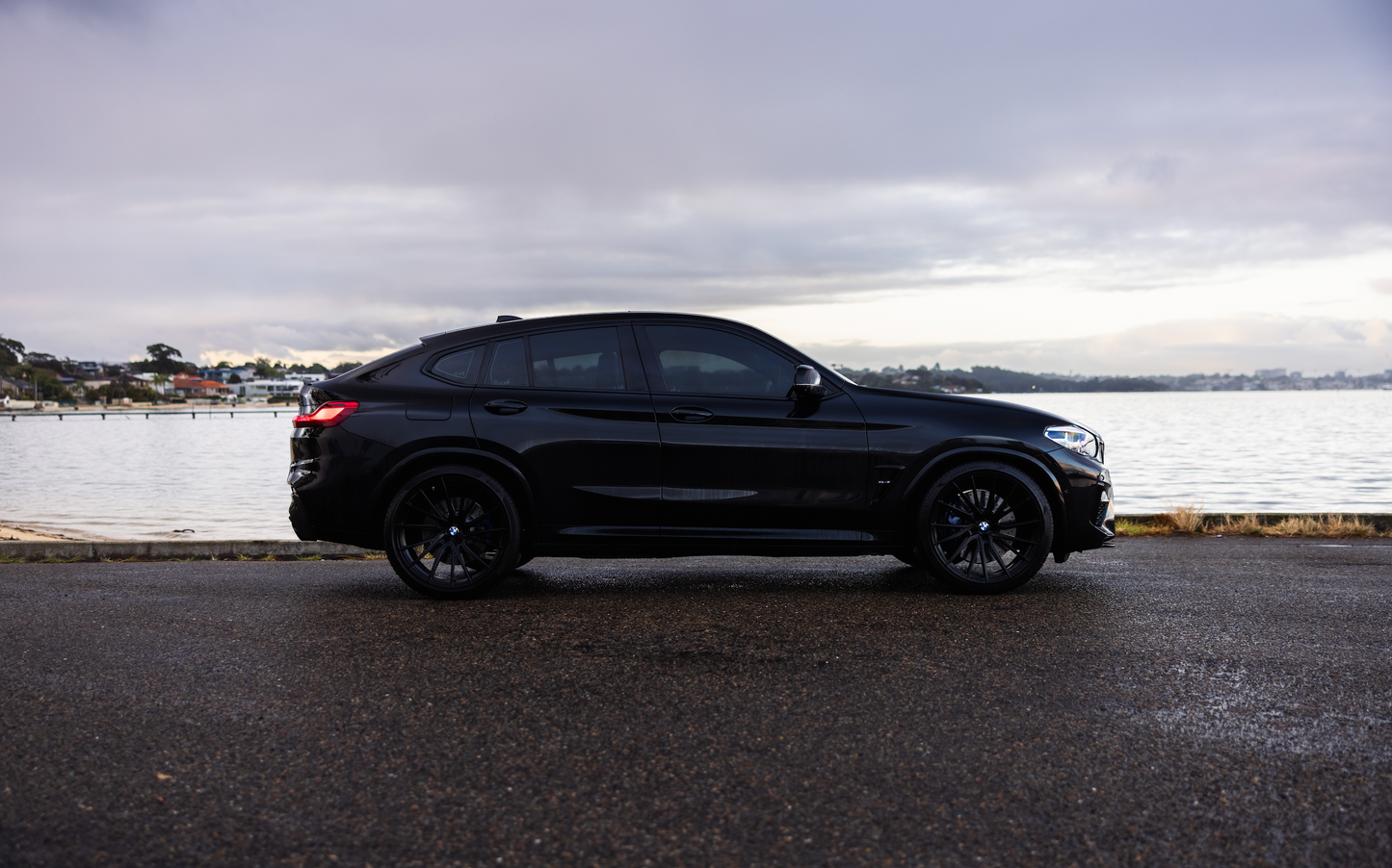 Black SUV parked by a waterfront on a cloudy day