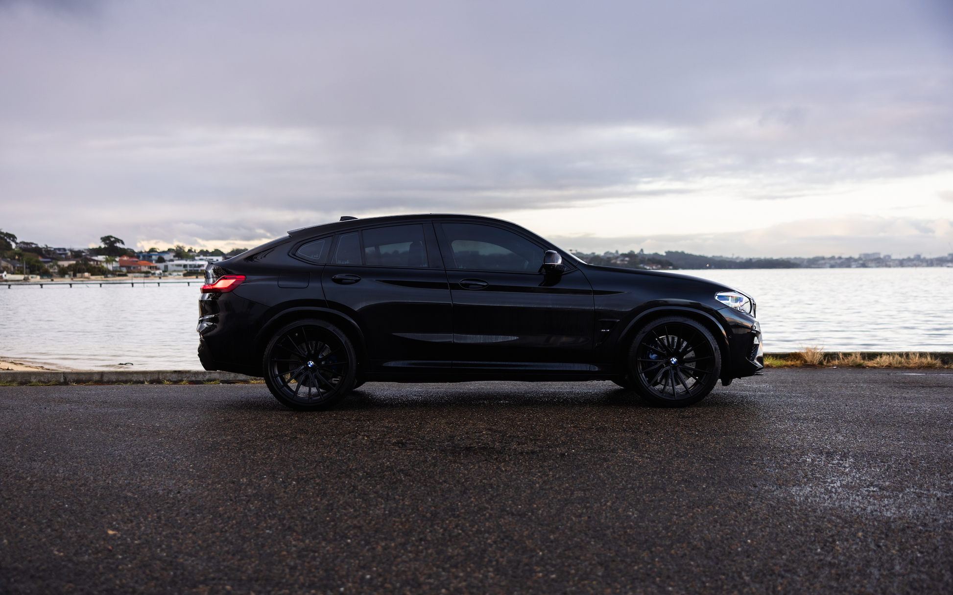 Black SUV parked by a waterfront on a cloudy day
